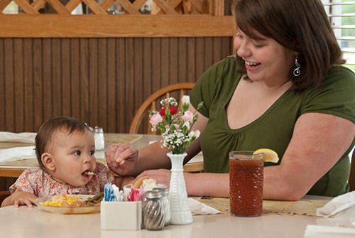 Mother feeding baby from plate at restaurant